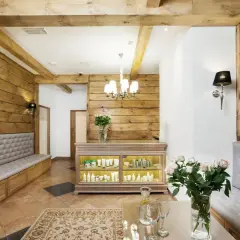 Wnętrze spa z drewnianymi elementami, kanapami, ladą z kosmetykami i bukietem róż.
